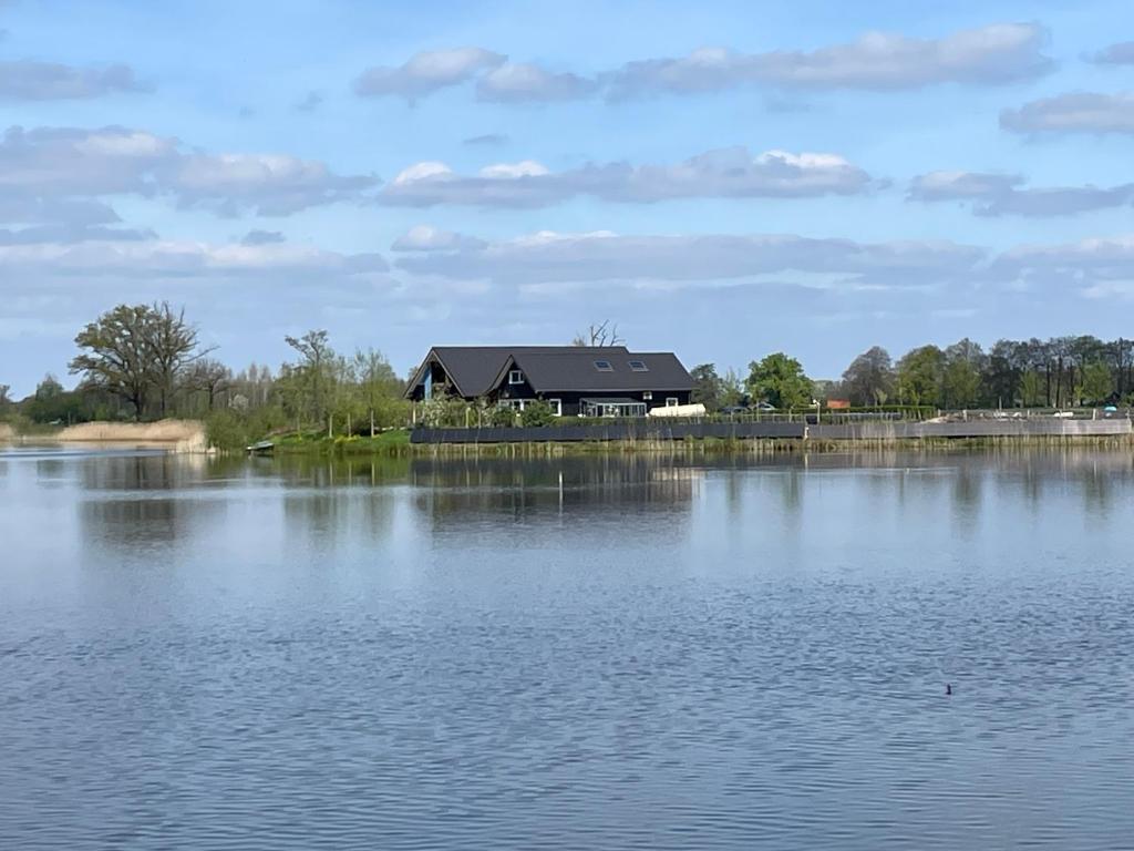 a house sitting on the edge of a lake at Het Riethuis in Holthone