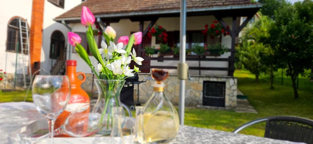 un tavolo con un vaso di fiori e bottiglie sopra di Vila Lena Banja Vrujci a Berkovac