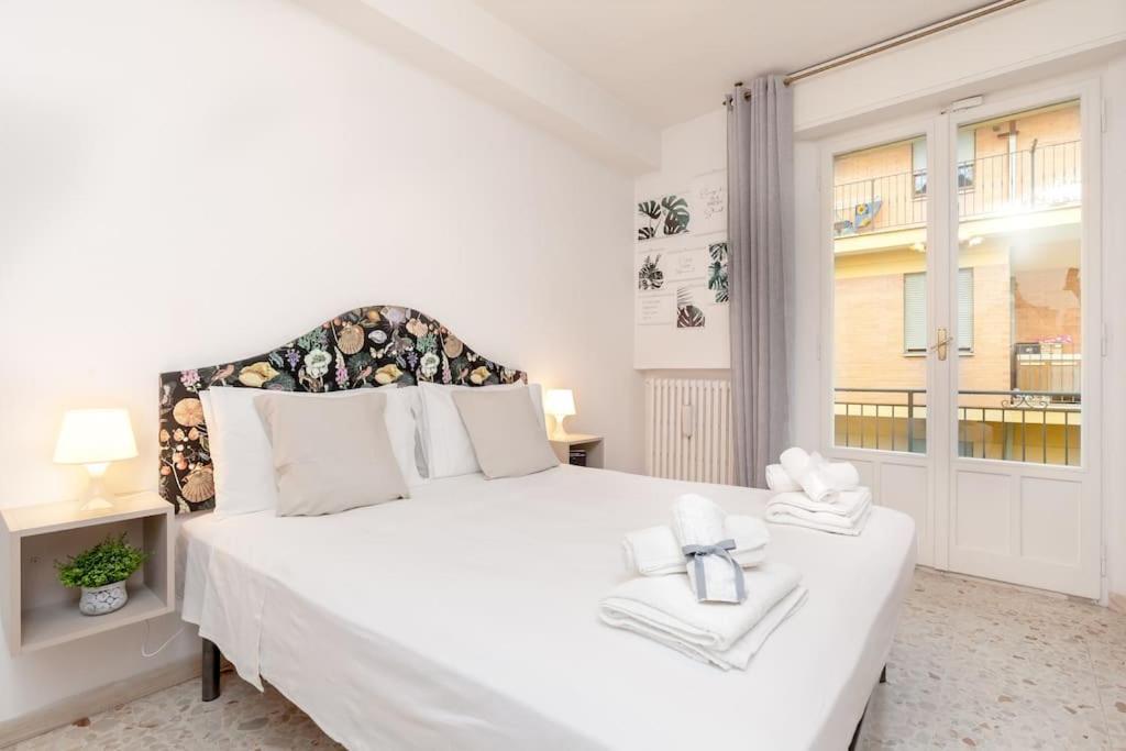 a white bedroom with a large white bed and a window at [RELAX- 7 POSTI] A pochi passi dal mare in Porto San Giorgio