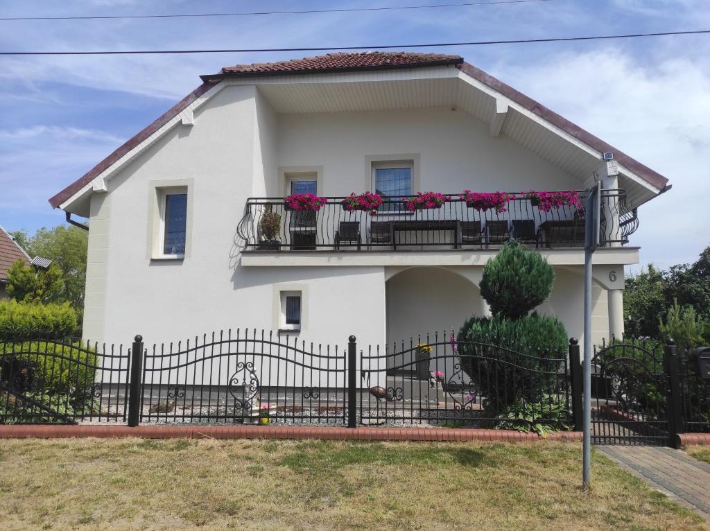 a white house with flowers on the balcony at Pokoje gościnne Cuma in Łeba