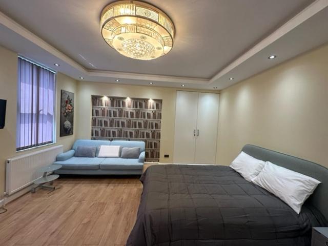 a bedroom with a bed and a couch and a chandelier at Lovely apartment near Gatwick airport in Reigate