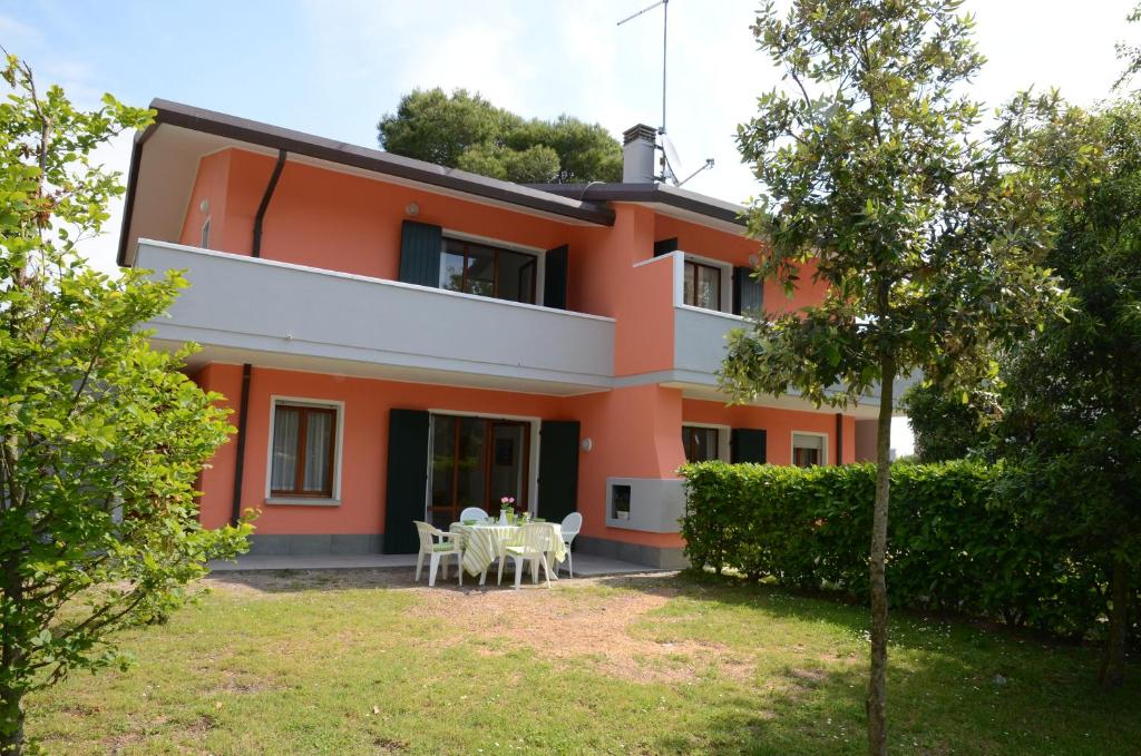 una casa arancione con un giardino di fronte di Ville Maitè a Bibione