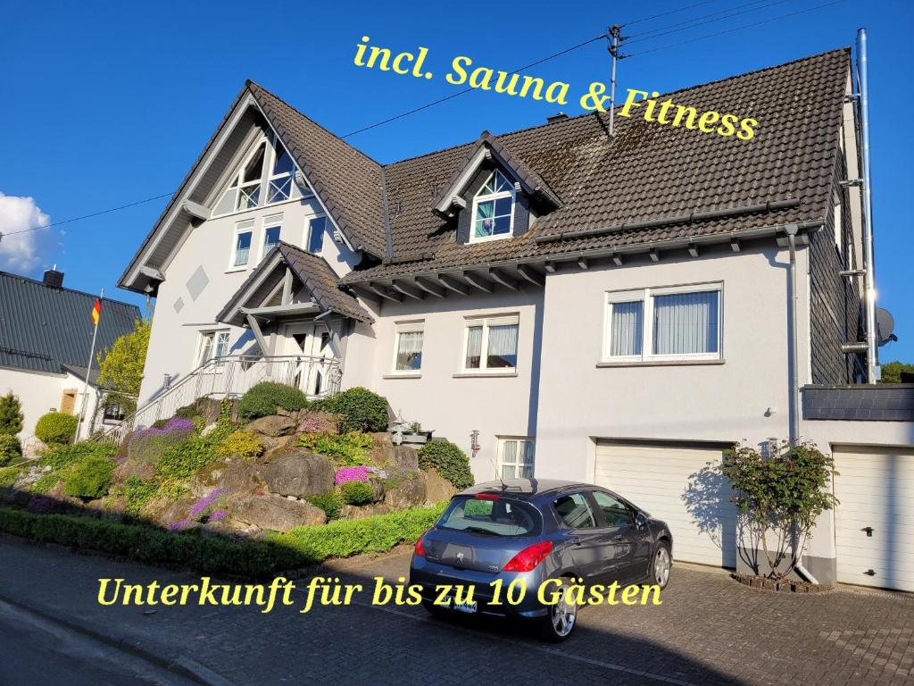 uma casa com um carro estacionado em frente em Ferienwohnung Fitness Entspannung Sauna im Westerwald em Derschen