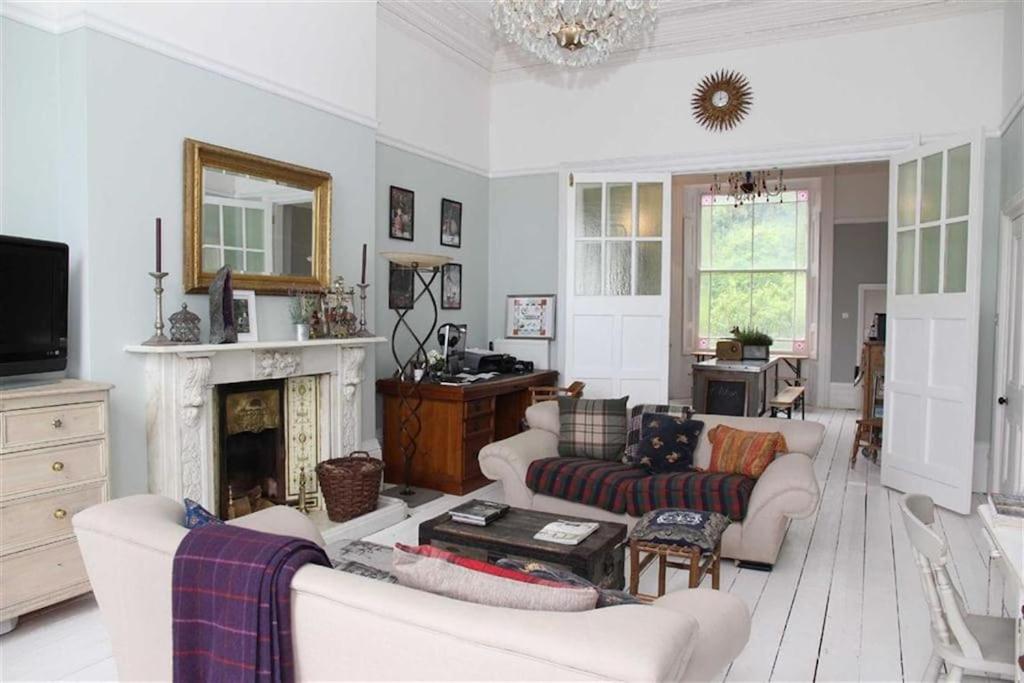 a living room with white furniture and a fireplace at Stunning Period & Family Apartment by the Sea in St. Leonards