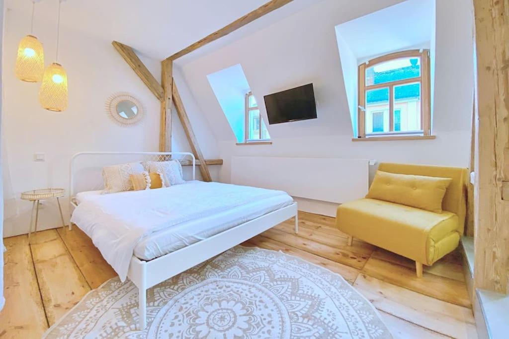 a bedroom with a white bed and a yellow chair at Zentrale 1-Zimmer-Ferienwohnung mit digitalem Check in in Hof