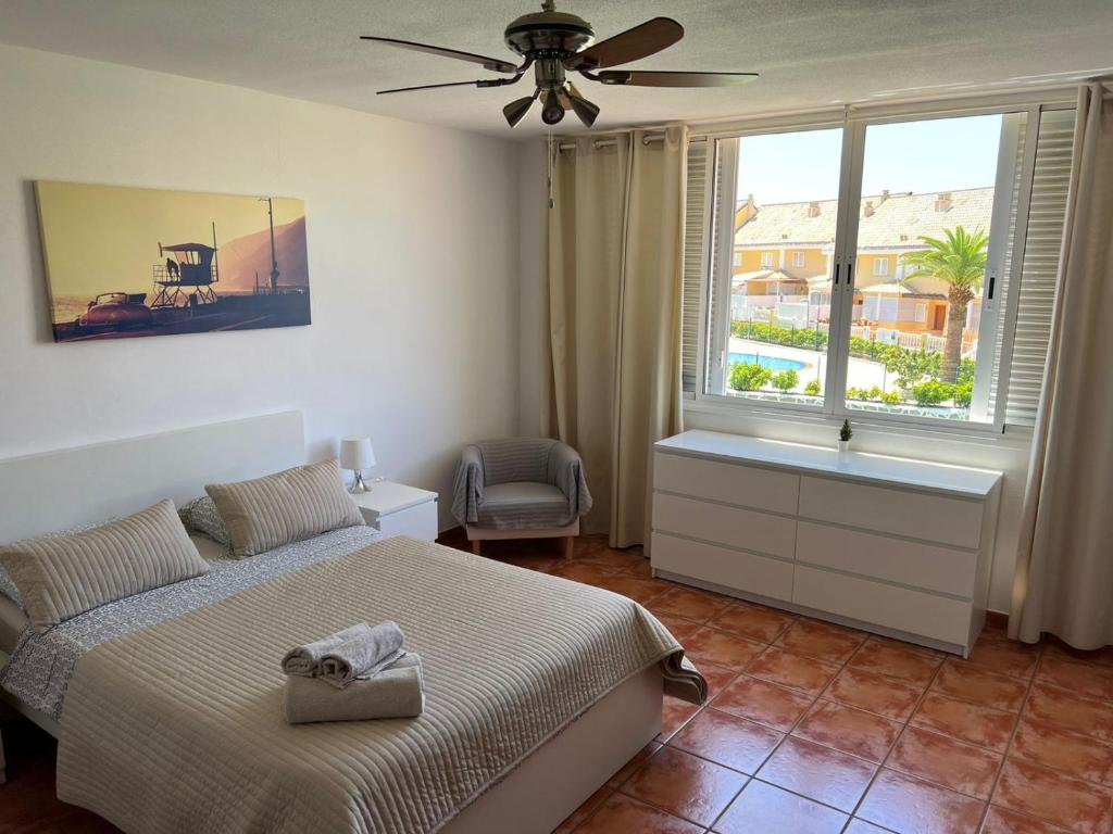 1 dormitorio con 1 cama con ventilador y ventana en El Camison Apartment, en Playa de las Américas