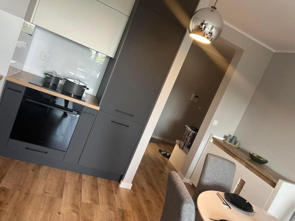 a kitchen with a stove top oven next to a living room at Apartament Nowoczesny w Centrum Torunia/podziemny parking i winda in Toruń