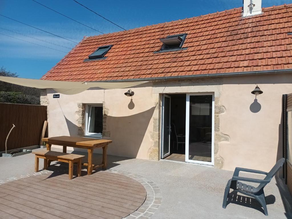 een patio met een houten tafel en een huis bij Ancienne maison de pêcheurs in Saint-Marcouf