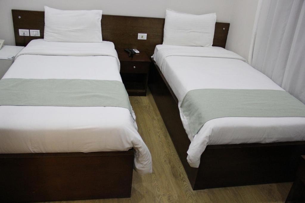 two beds in a hotel room with white sheets at Miramar Downtown in Cairo