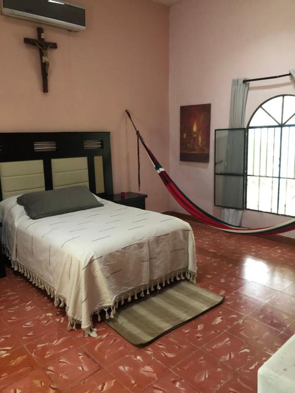1 dormitorio con 1 cama y 1 cruz en la pared en Casa de campo Hacienda Multunkú Minerva, en Seyé