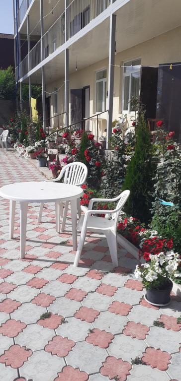 two white benches sitting in front of a building with flowers at СафияGold in Cholpon-Ata