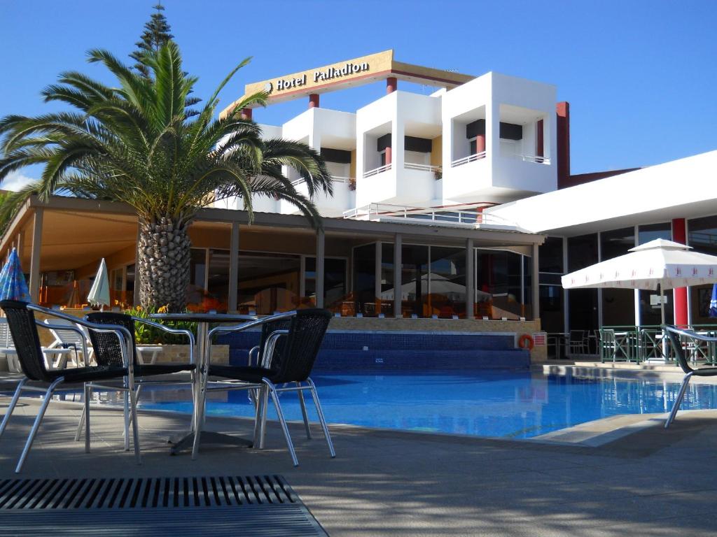 een resort met een zwembad en een palmboom en stoelen bij Palladion in Adelianos Kampos
