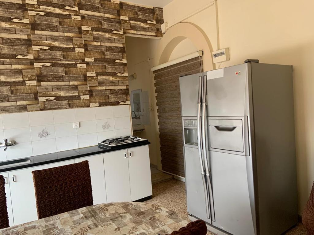 La cuisine est équipée d'un réfrigérateur en acier inoxydable et de placards blancs. dans l'établissement Downtown Apartment, à Bayt Sāḩūr