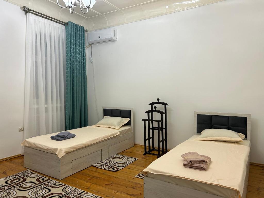 two beds in a room with white walls and wood floors at Humo Family Home in Tashkent