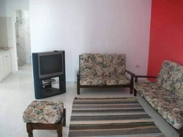 uma sala de estar com duas cadeiras e uma televisão em Mahdia zone Touristique em Mahdia