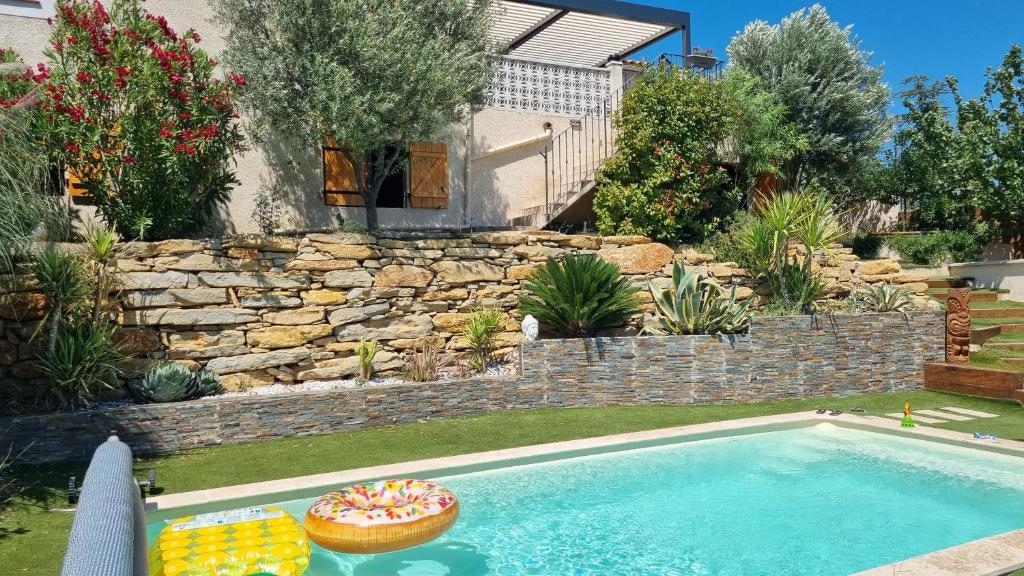 a swimming pool in a yard with a stone retaining wall at Magnifique villa avec piscine et vue panoramique in La Destrousse