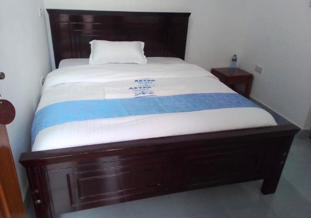 uma cama com um cobertor azul e branco em Aster Suites Kisumu em Awasi