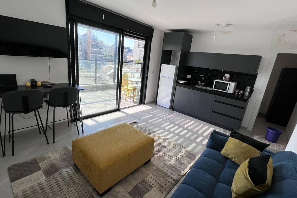 a living room with a blue couch and a kitchen at New Large STUDIO flat in Tel Aviv 47 in Tel Aviv