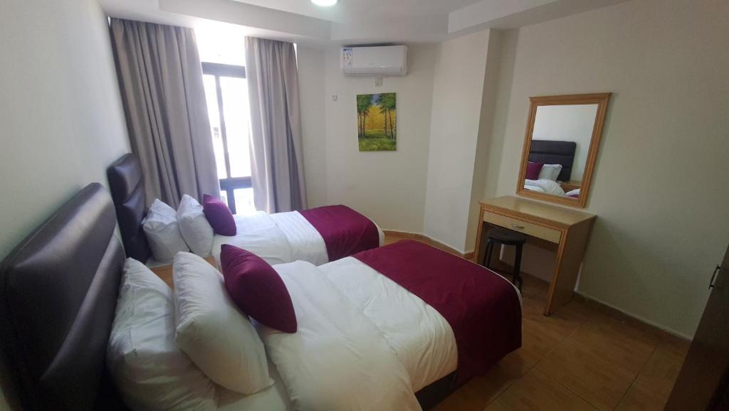 una camera d'albergo con due letti e uno specchio di Red Carpet 2 ad Amman