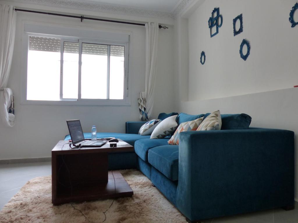 een woonkamer met een blauwe bank en een tafel bij EXCELLENT rapport Qualité Prix pour cet Appartement 3 étoiles Neuf 2P Tout Confort Résidence Golf Mesnana Tanger in Tanger