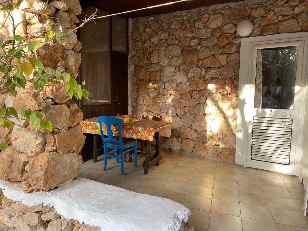 a dining room with a table and chairs in a stone wall at Villaggio La Roccia camping in Lampedusa