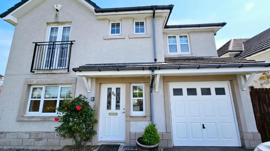 a white house with white garage doors at 26 Woodgrove Drive in Inverness