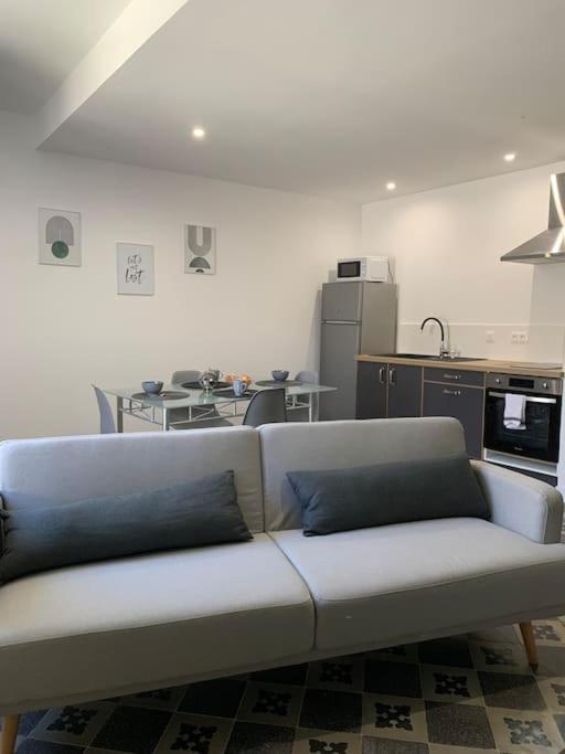 - un canapé blanc dans une chambre avec cuisine dans l'établissement Appartement cœur de village Numéro2, à Peyriac-de-Mer