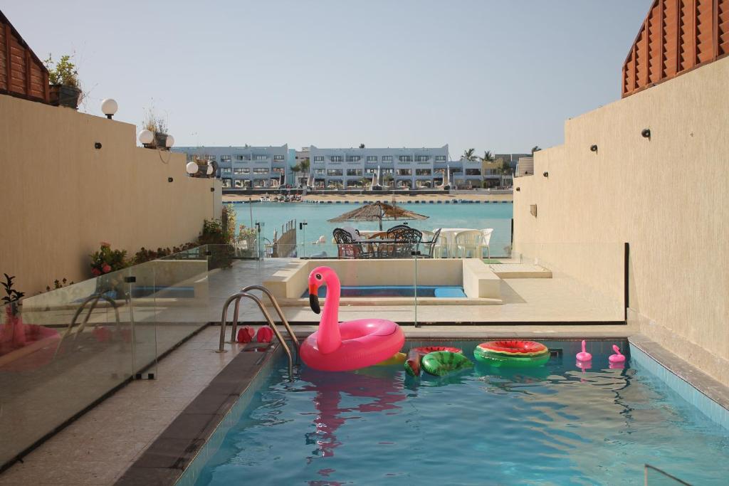 a swimming pool with a pink swan in the water at Rose Beach Villas in Durat Alarous