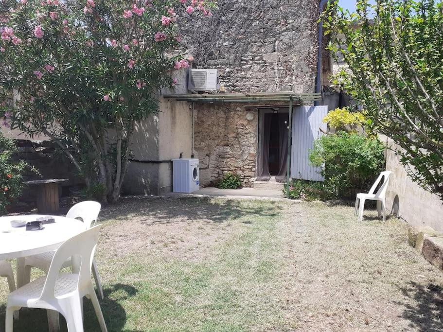 - un jardin avec une table et des chaises en face d'un bâtiment dans l'établissement Maison de village - grand jardin, à Saint-Quentin-la-Poterie