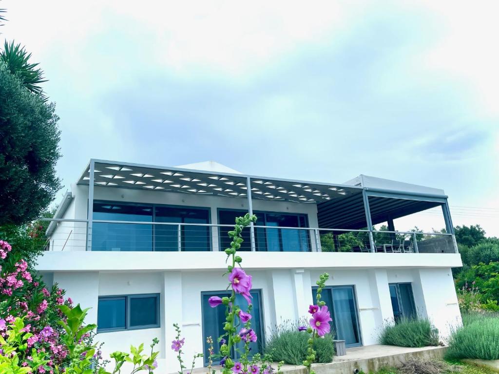 Cette maison blanche dispose d'un balcon et de fleurs violettes. dans l'établissement Luxury Villa set in Idyllic Cove, sunets, dolphins Nr Lefkada Villa Levanda, à Spartos
