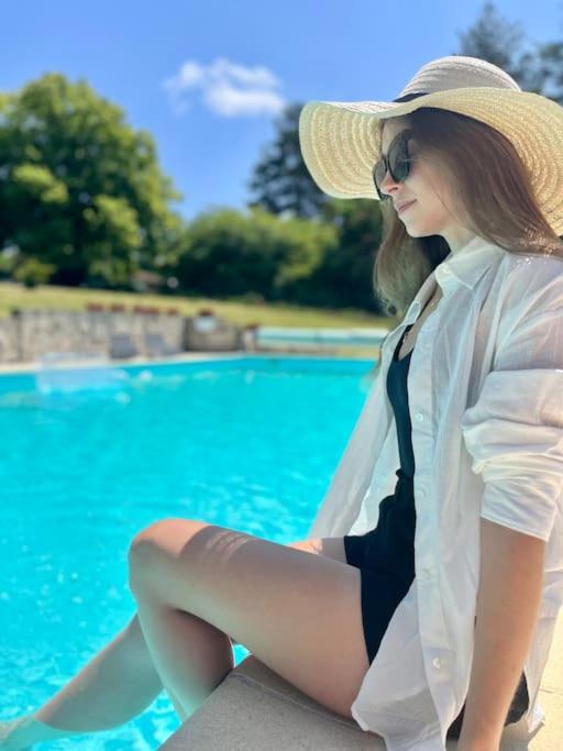 une femme avec un chapeau et une cravate assise à côté d'une piscine dans l'établissement 3-4 Cottages Entire Site Private Pool for Relaxing Holidays & Special Occasions near Aubeterre, à Saint-Romain