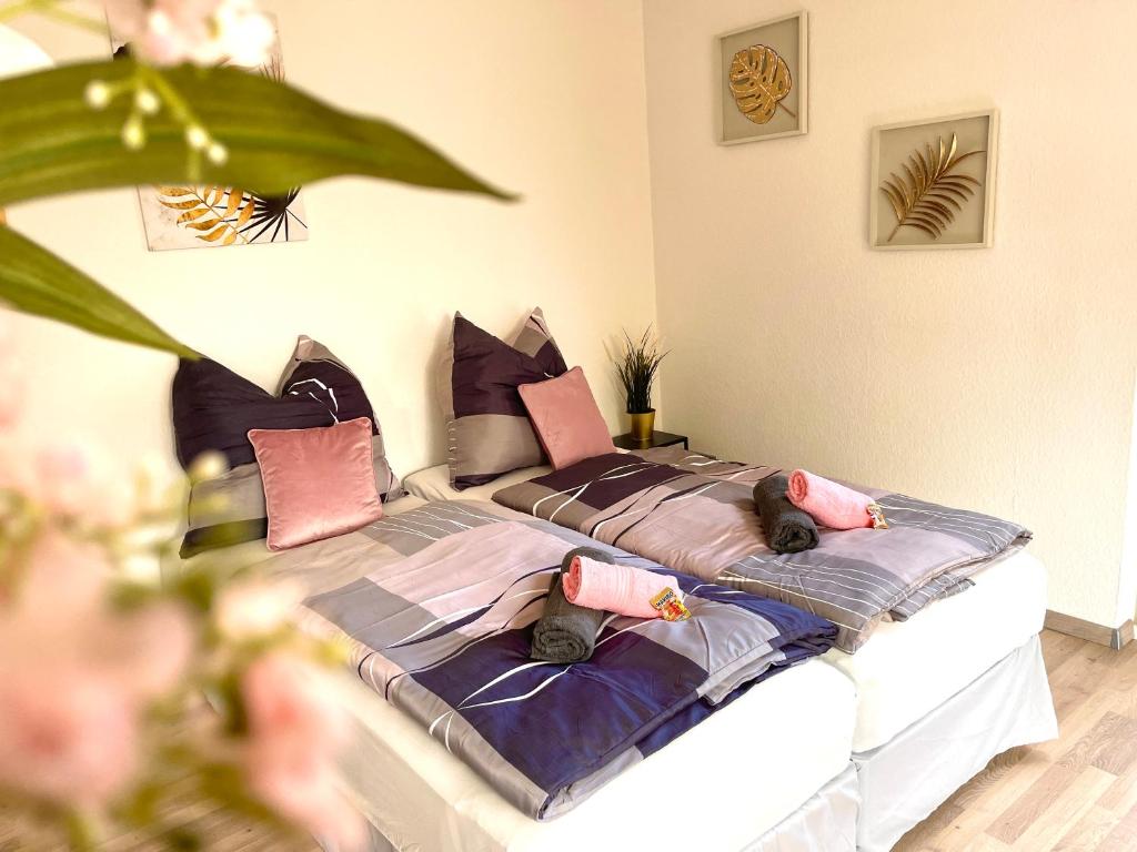 Zuhause im Ruhrgebiet 2 mit Balkon في أوبرهاوزن: غرفة نوم مع سرير مع وسائد وردية وأرجوانية