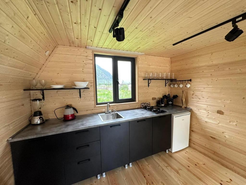 a kitchen in a wooden cabin with a sink and a window at Thomas' Hut in Stepantsminda