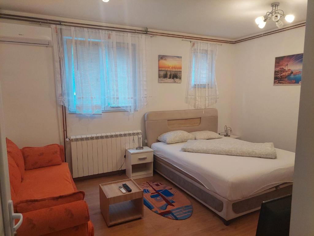 een kleine slaapkamer met een bed en een stoel bij Apartman Anastasija in Surčin