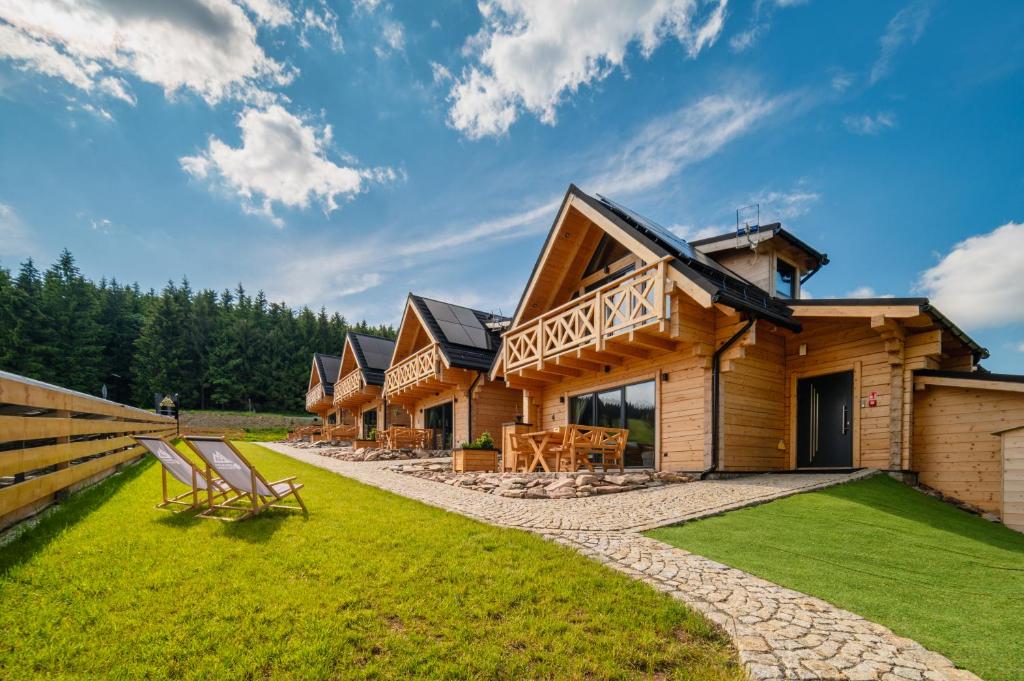 une cabane en rondins avec une cour gazonnée devant elle dans l'établissement Domki Osada Zieleniec, à Duszniki-Zdrój