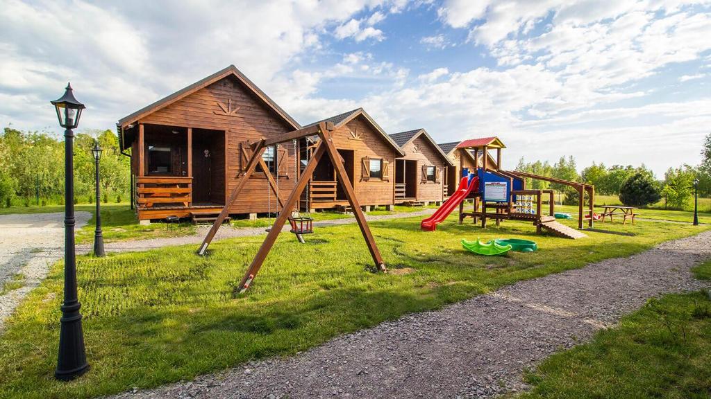 a group of log homes with a playground at Sielankowe Domki in Rusinowo