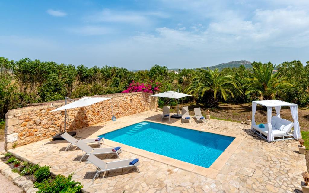 een villa met een zwembad en een patio met stoelen bij Borgata Roggio in Sineu