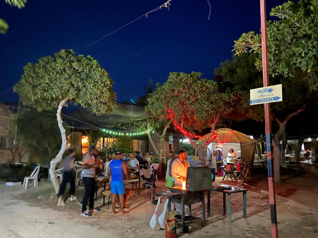 a group of people sitting at a restaurant at night at Villaggio La Roccia camping in Lampedusa
