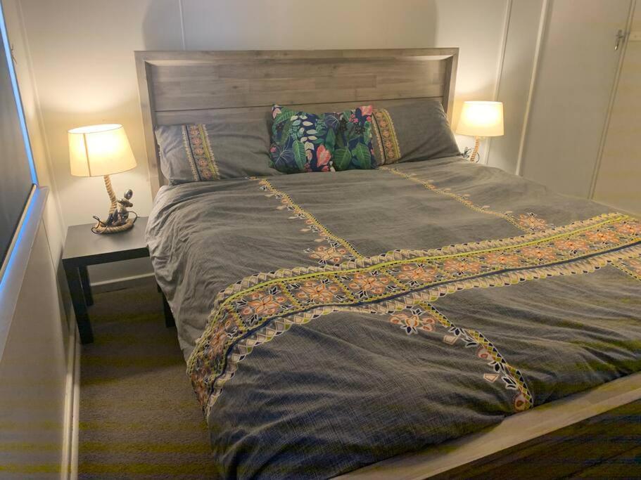 a large bed in a bedroom with a table and two lamps at dhu drop inn in Cervantes