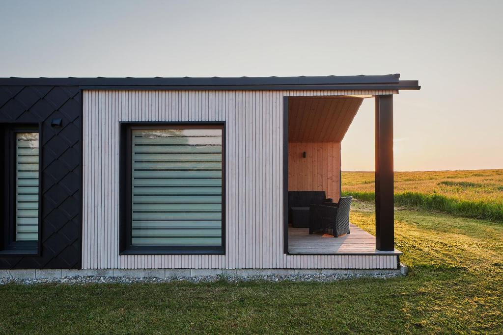 ein kleines Haus mit einer Terrasse im Gras in der Unterkunft Modernes Tiny House -neu 2021- in Uigendorf