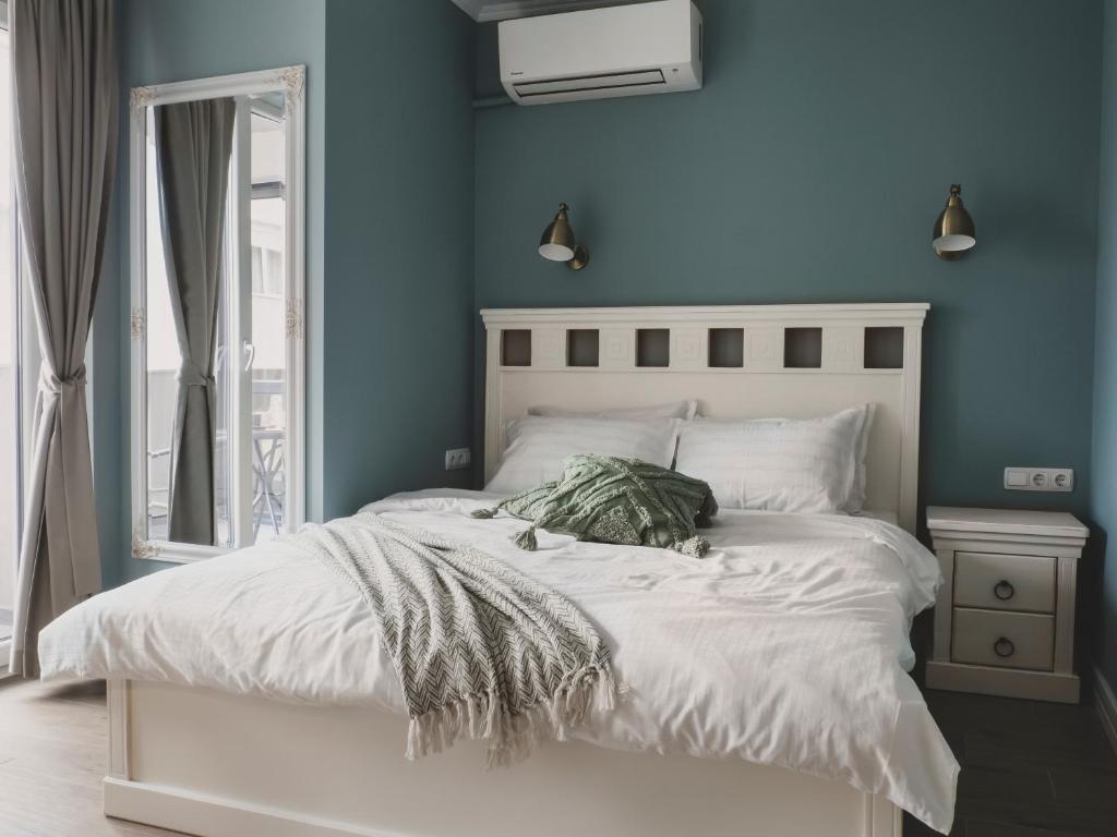 um quarto com uma cama branca e uma parede azul em Stylish 1BD - Free Private Garage em Plovdiv