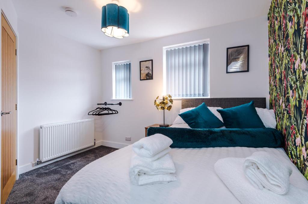 a bedroom with a large white bed with blue pillows at 4 bed property, Bolton , Manchester in Egerton