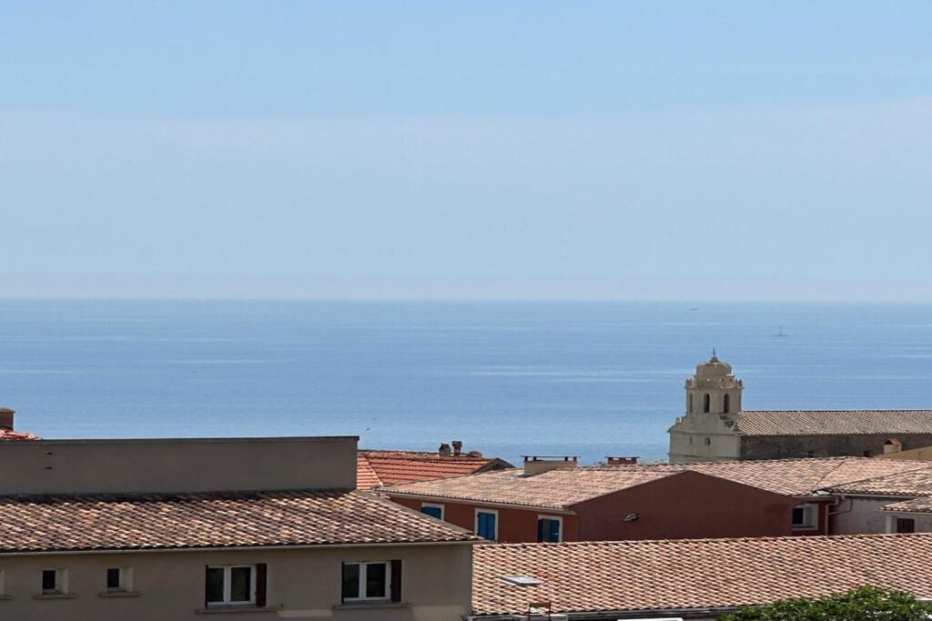 a view of roofs of a city with a clock tower at Alivu - Appartement Moderne Avec Terrasse in Cargèse