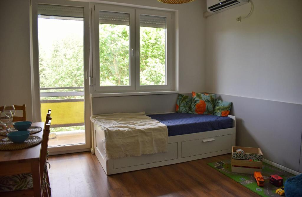 a bedroom with a bed with a window and a table at Helikon 31 Apartman Keszthely in Keszthely