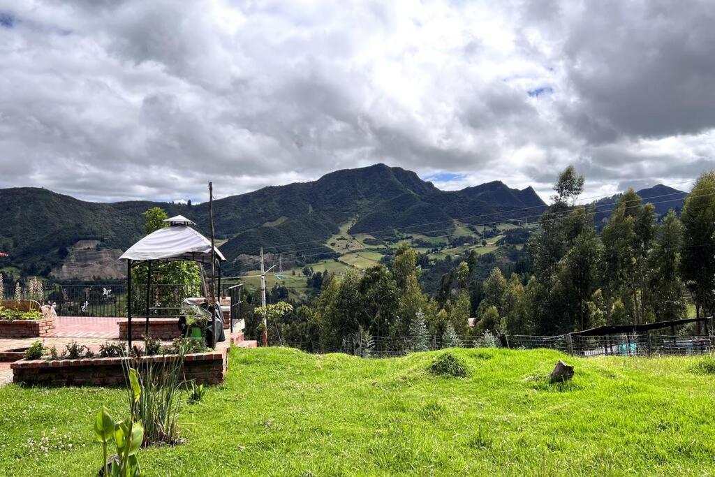 a field with a gazebo on a hill with mountains at Cabaña en la montaña de 3 Habitaciones in Sutatausa