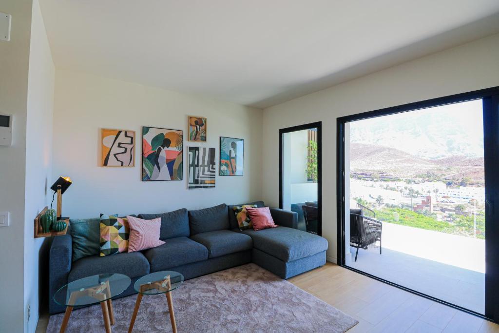 - un salon avec un canapé bleu et une grande fenêtre dans l'établissement Paramount views Agaete apartment, à Puerto de las Nieves
