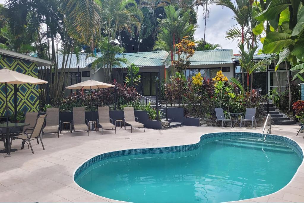 einen Pool mit Stühlen, einem Tisch und einem Gebäude in der Unterkunft Tico Tico Villas - Adult Only in Manuel Antonio