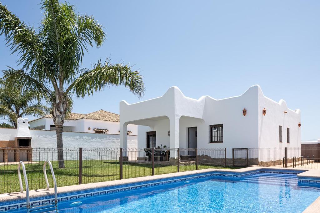 a villa with a swimming pool in front of a house at Villa Cala Salada in Conil de la Frontera