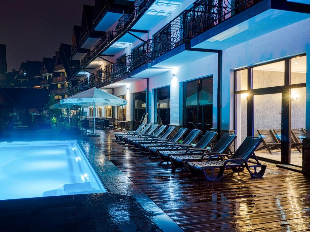 a row of lounge chairs next to a swimming pool at Hotel Paryski Art & Business Zakopane - Basen Jacuzzi Sauna Małpi Gaj in Zakopane