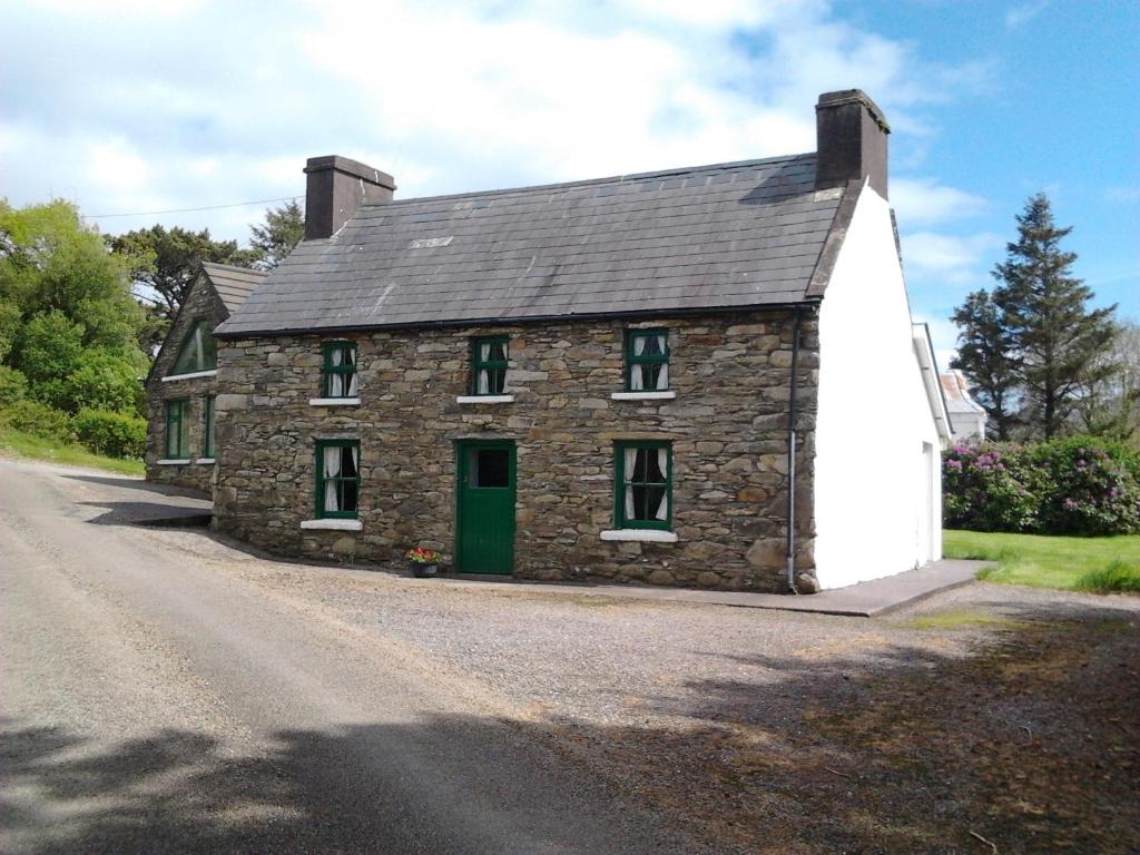 a stone house with a green door on a road at Westland Traditional Cottage dated 1700's in Ardea